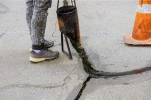 Driveway Crack Repair by a worker with sealcoating tool