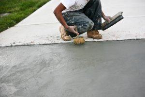 Paving Driveway by a worker with two brushes